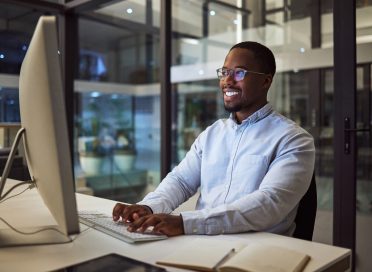 Happy, computer and african businessman typing on a keyboard for corporate research in his office. .